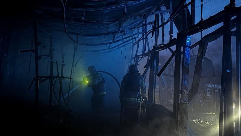 Two Ukrainian rescuers work at the site of an air attack.